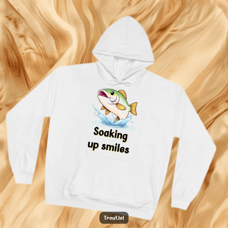 Funny hoodie depicting a shimmering trout with a broad, beaming smile, joyfully leaping from a splash, bringing aquatic cheer and warmth.